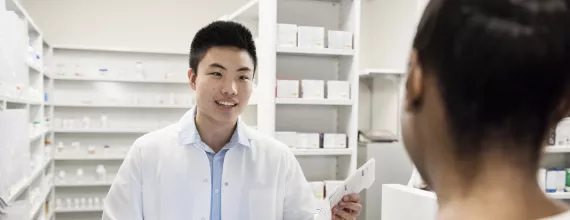 Pharmacist handing prescription to customer