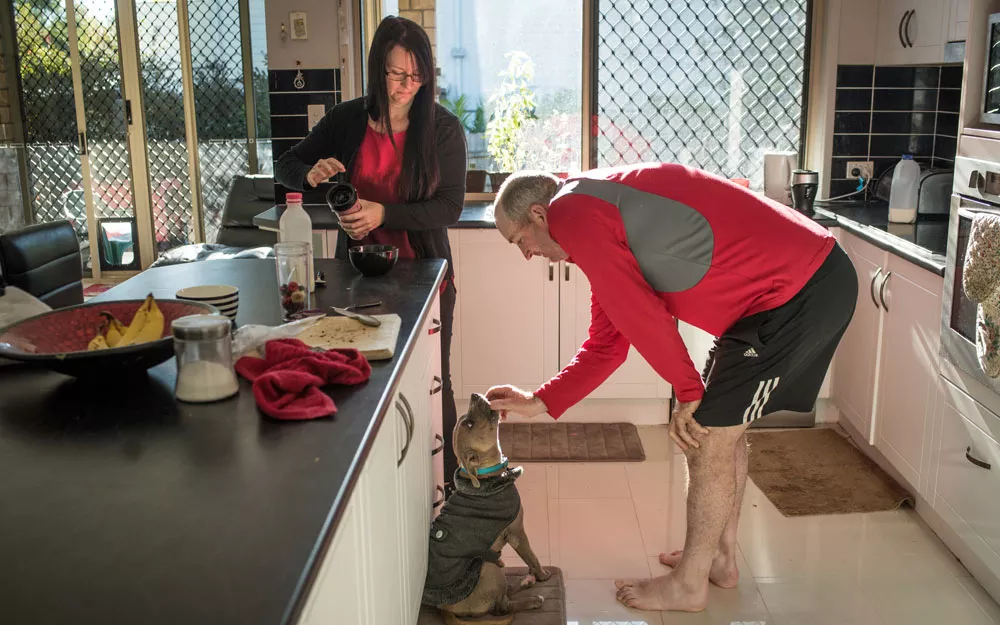 Mr. Caddies and his wife prepare food and feed their dog in their kitchen