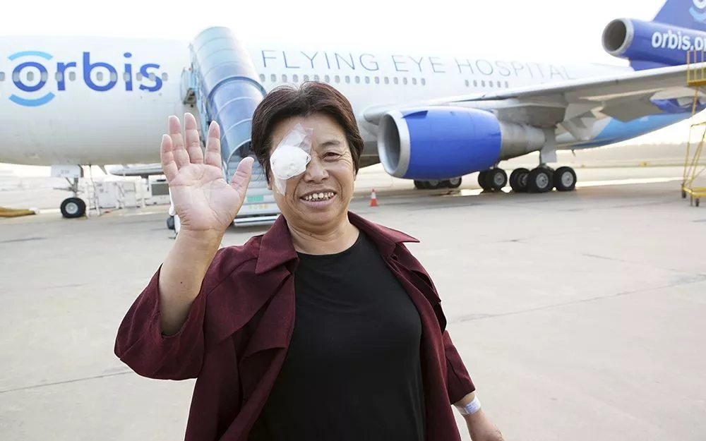 Mrs. Cao waves to the camera after exiting the flying hospital post-operation