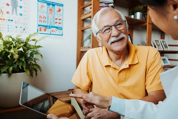 A healthcare professional and senior patient in a conversation using a tablet