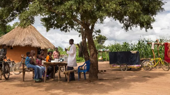 Healthcare worker, Dismus Mwalukwanda, discussing with a group of people in a rural part of Zambia