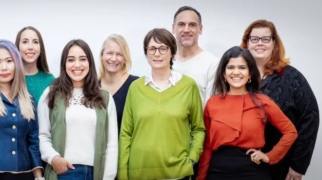 A group portrait of diverse Novartis volunteers in front of a white background, taken in the observance of International Volunteer Day 2022